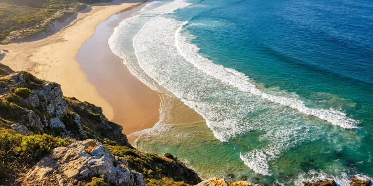 Por que as ondas do mar parecem sempre virar em direção à praia, mesmo quando o vento sopra de outro lado?